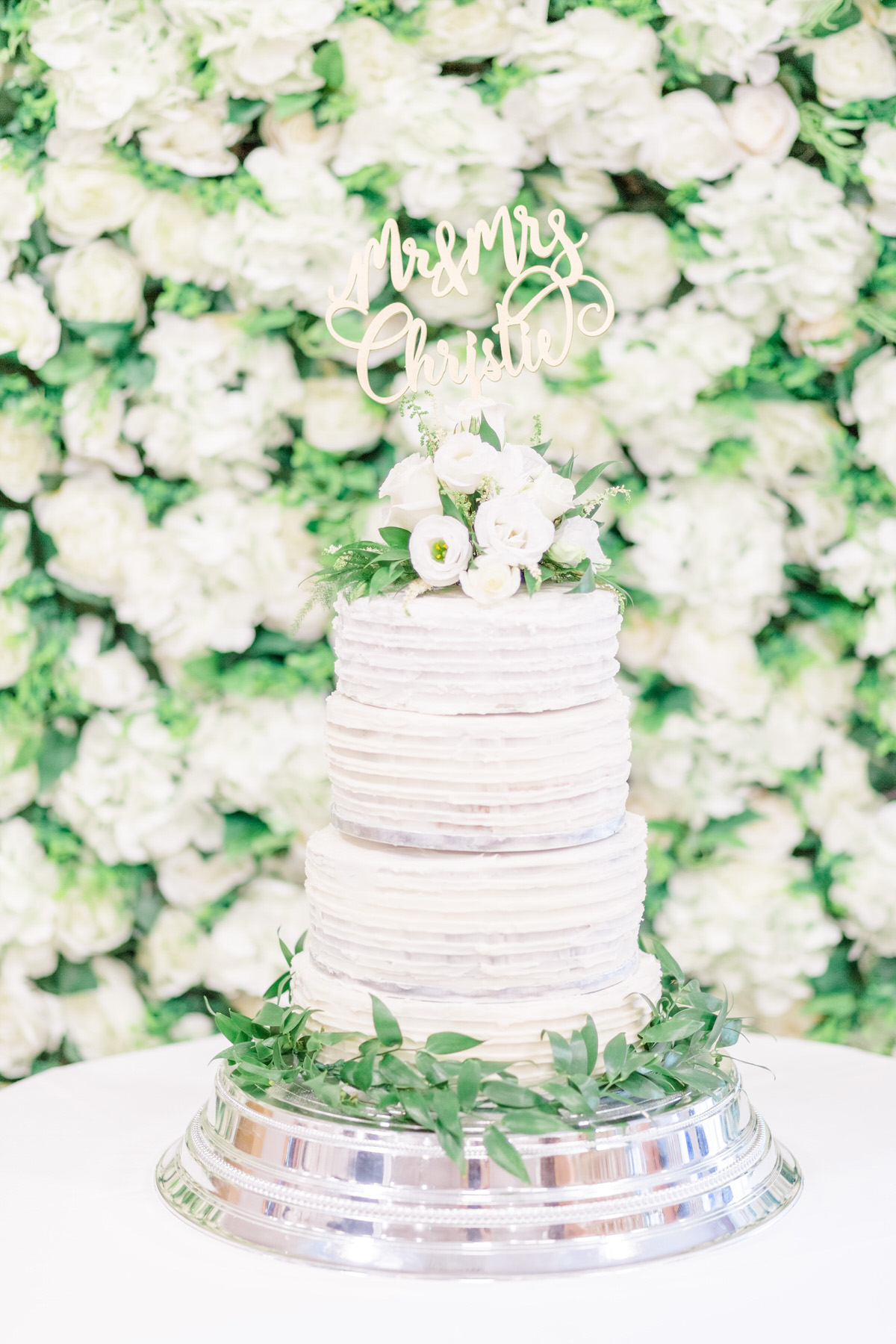 Buttercream wedding cake, elegant English wedding, flower wall, white flower wall, cutting the cake, navy and white wedding